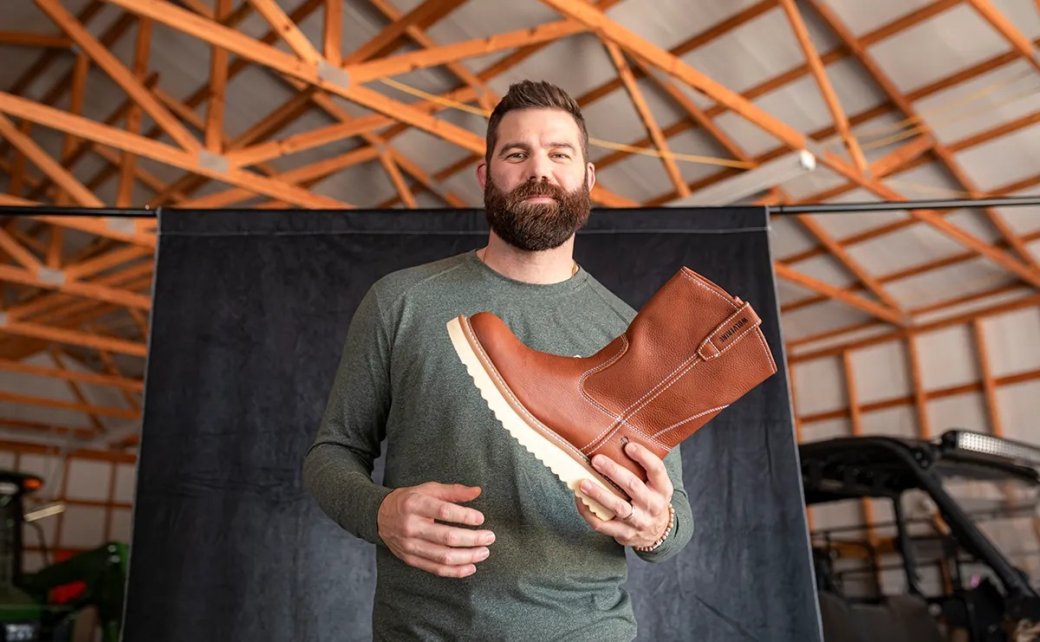 Джордан Дэвис держит рабочие ботинки Wolverine 10″ Wellington. Фото: Courtesy of Wolverine Boots